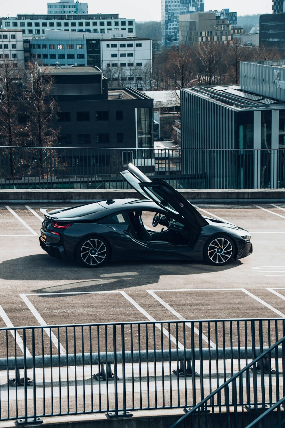 a black sports car parked in a parking lot with buildings in the background