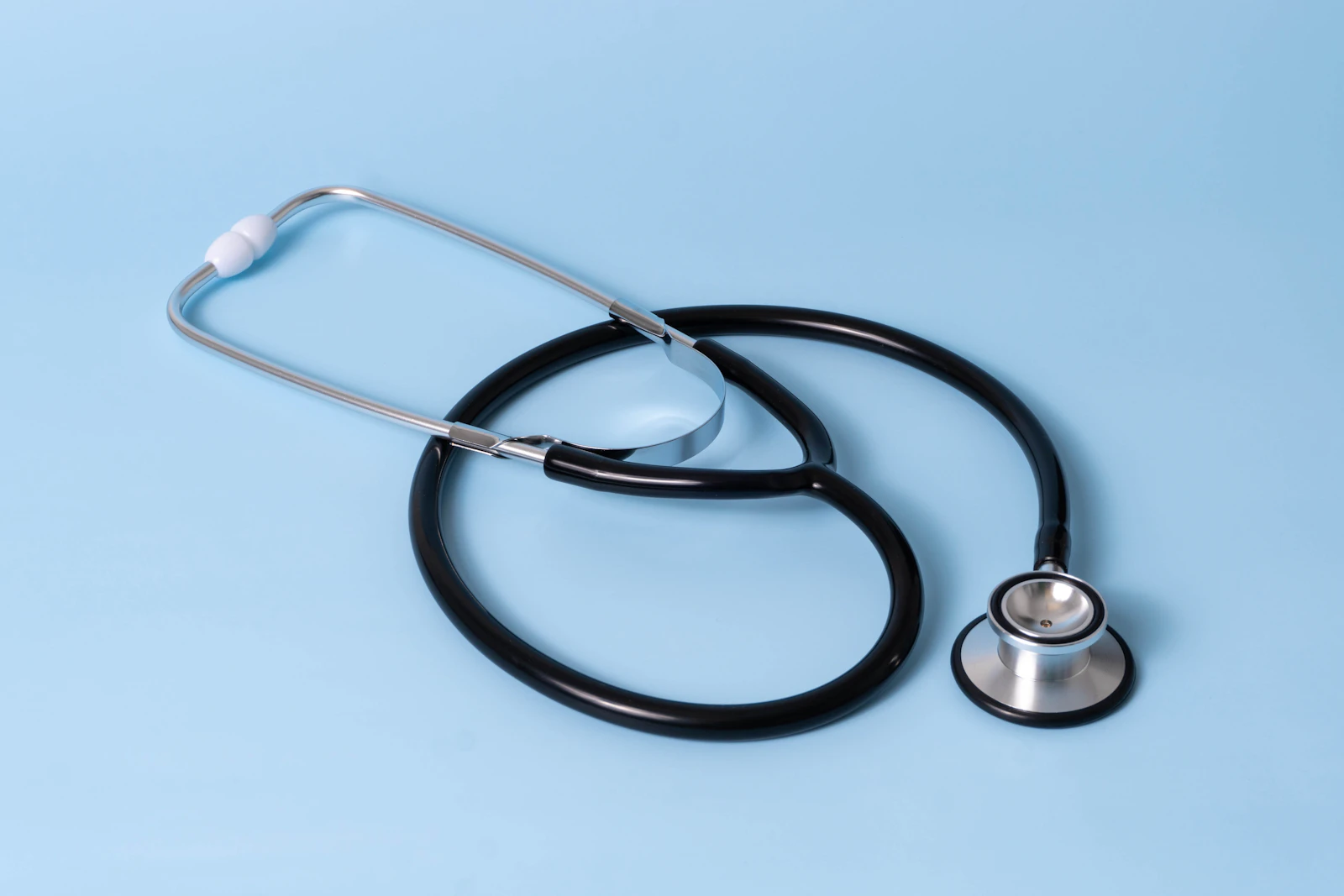 A black stethoscope on a pale blue surface
