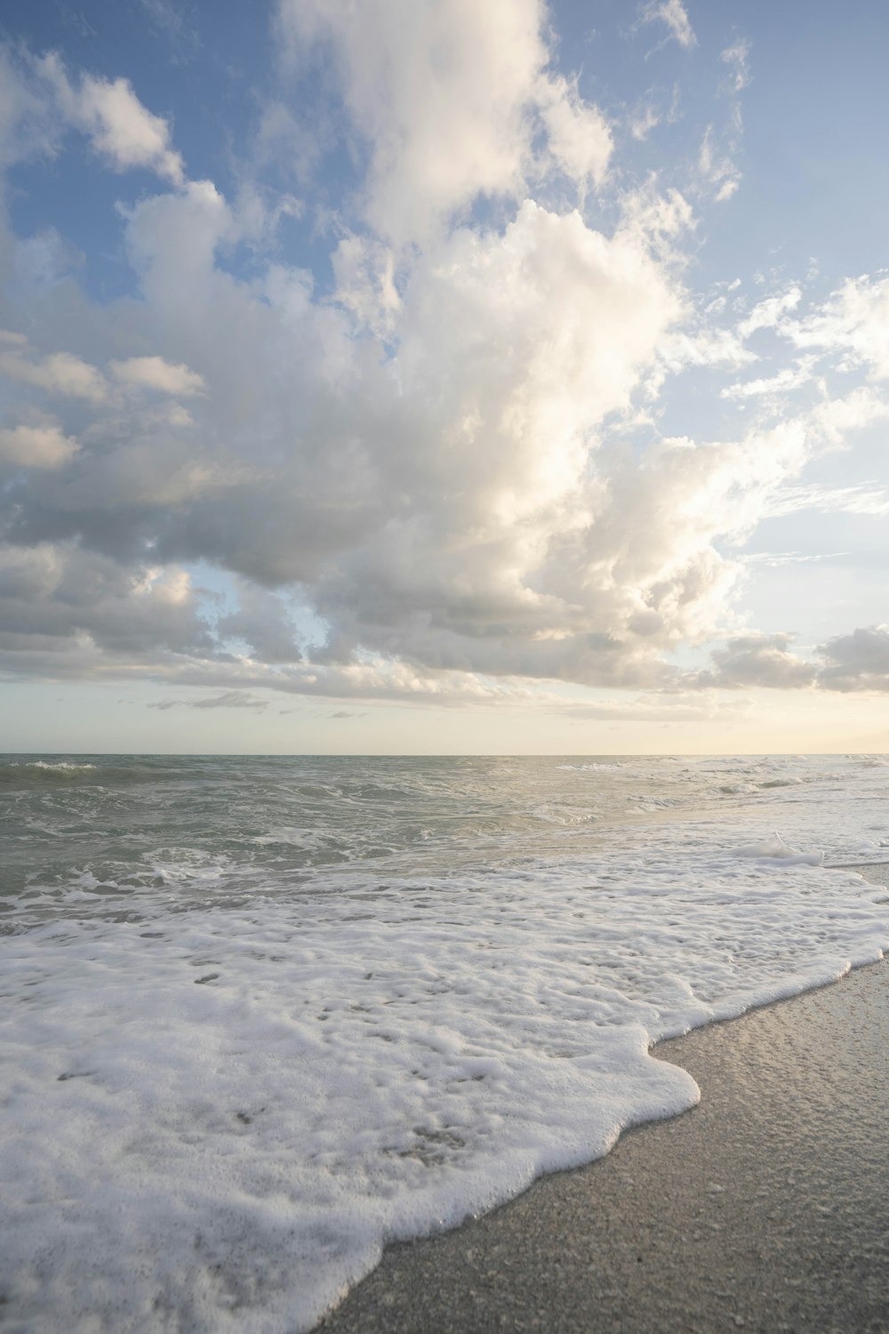 a beach with waves and clouds