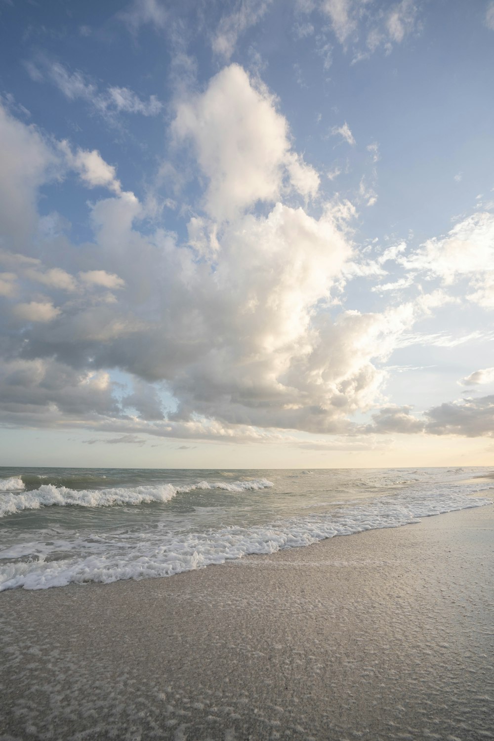 a beach with waves and clouds