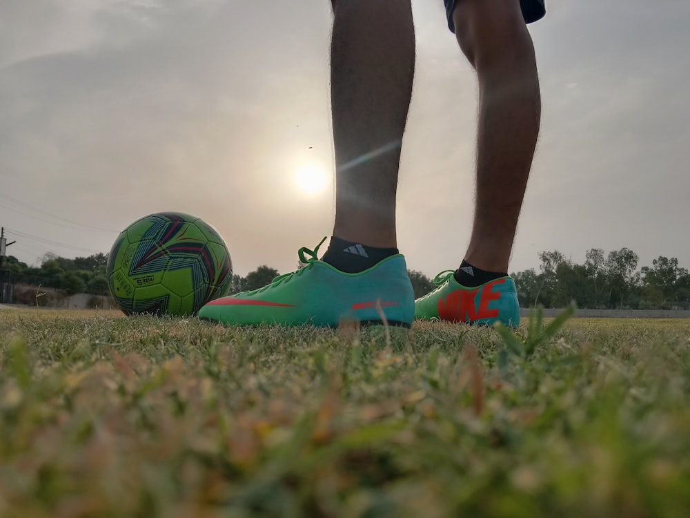 a person's legs and feet on a football ball in a field