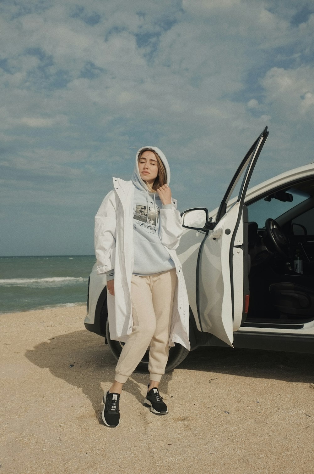 a man in a white coat standing next to a car on a beach