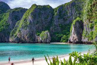 people walking on a beach with Phi Phi Islands in the background