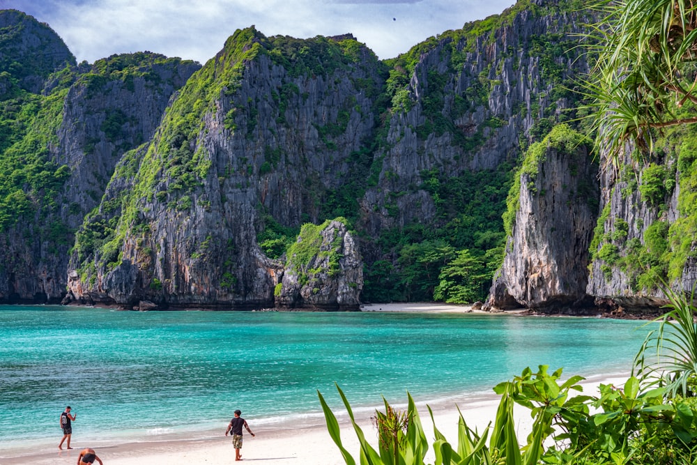 people walking on a beach with Phi Phi Islands in the background