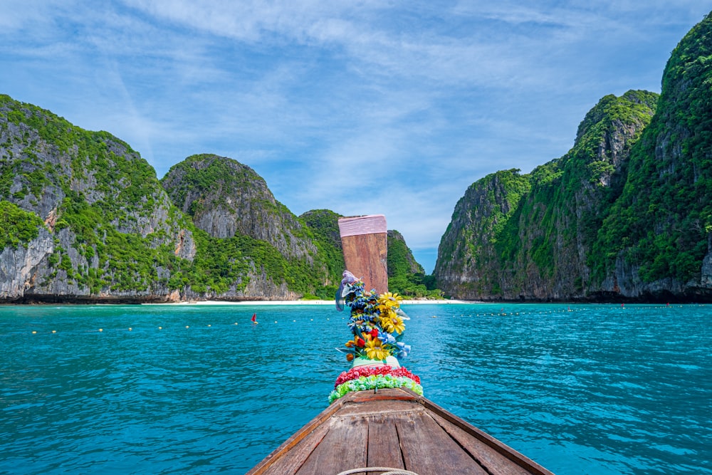 a boat with a bouquet of flowers on it in front of a body of water with mountains in