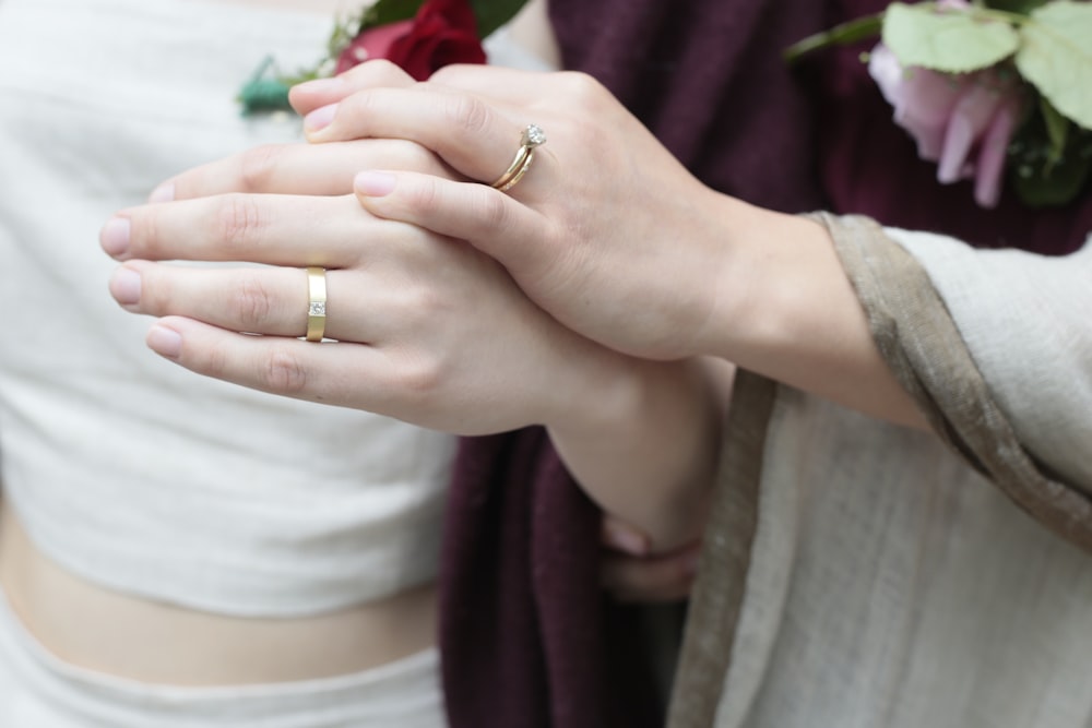 a pair of hands holding a wedding ring