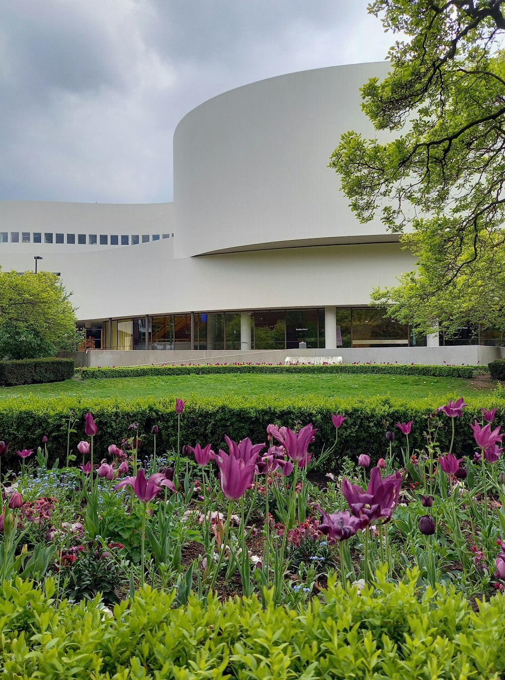 a building with a large lawn and flowers in front of it