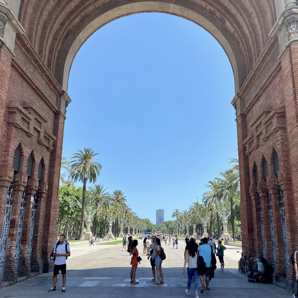 a group of people walking under a large archway