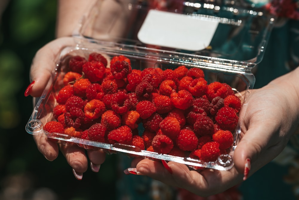 a person holding a container of strawberries