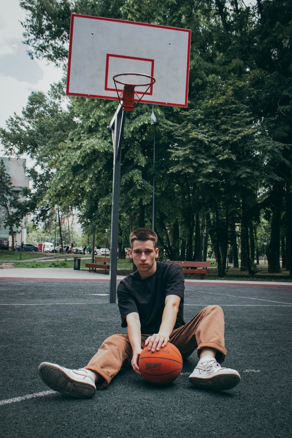 a man sitting on the ground next to a basketball hoop