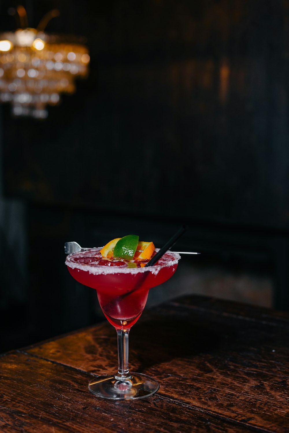 a glass of red drink with a lime wedge and a slice of lime