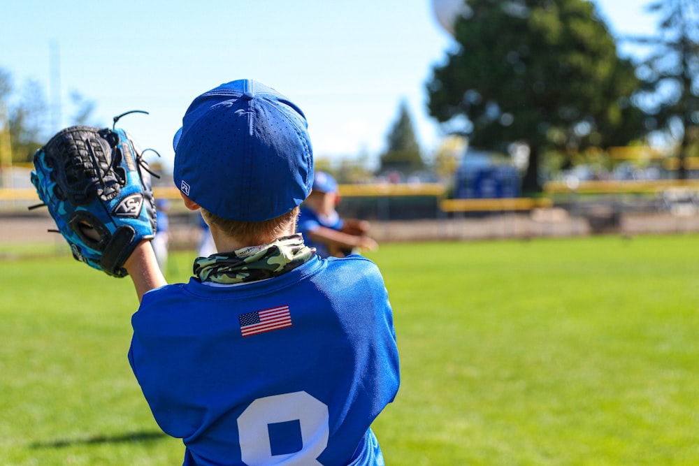 a kid in a baseball uniform holding a baseball glove