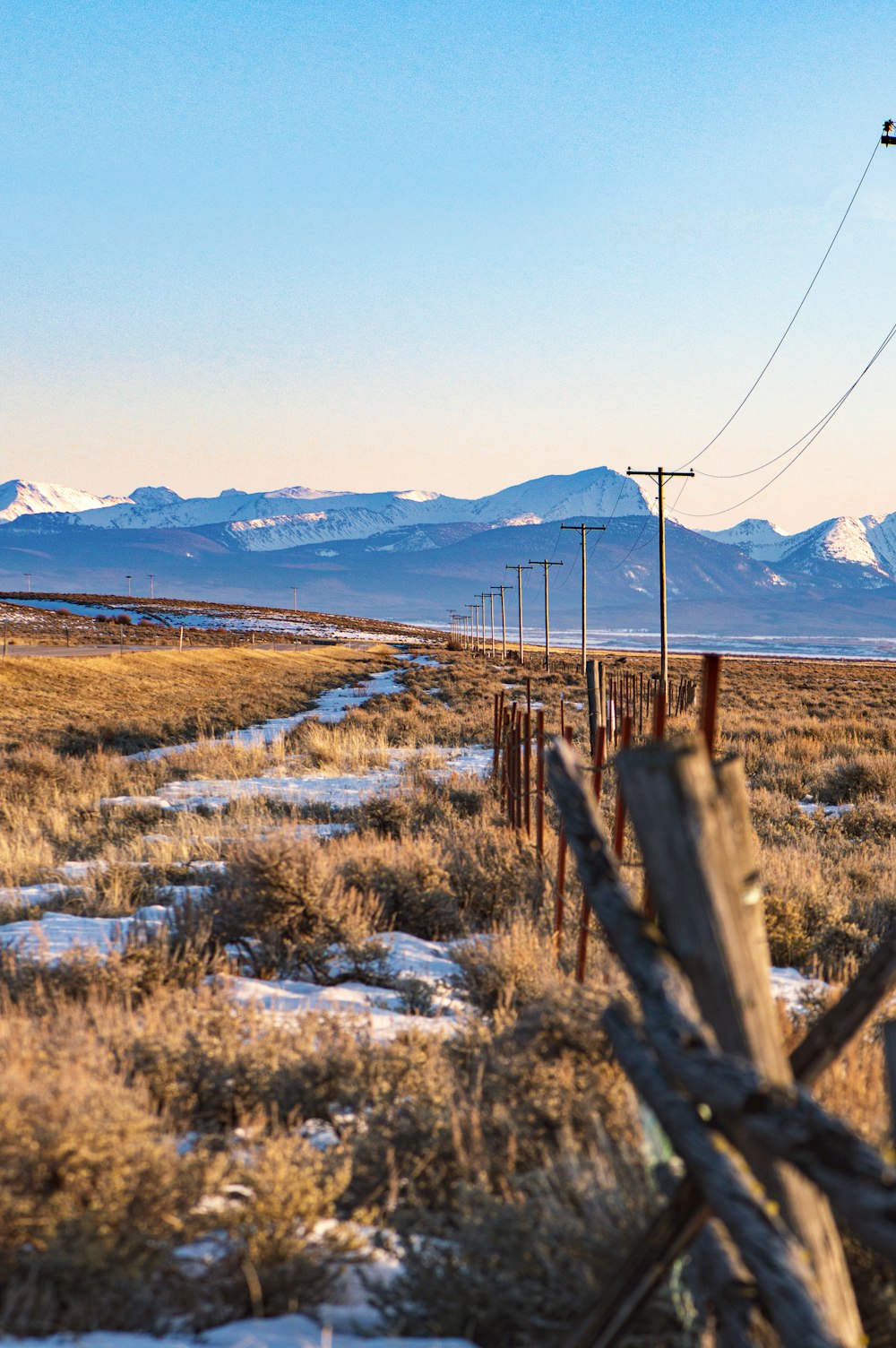 a fence in a field with mountains in the background