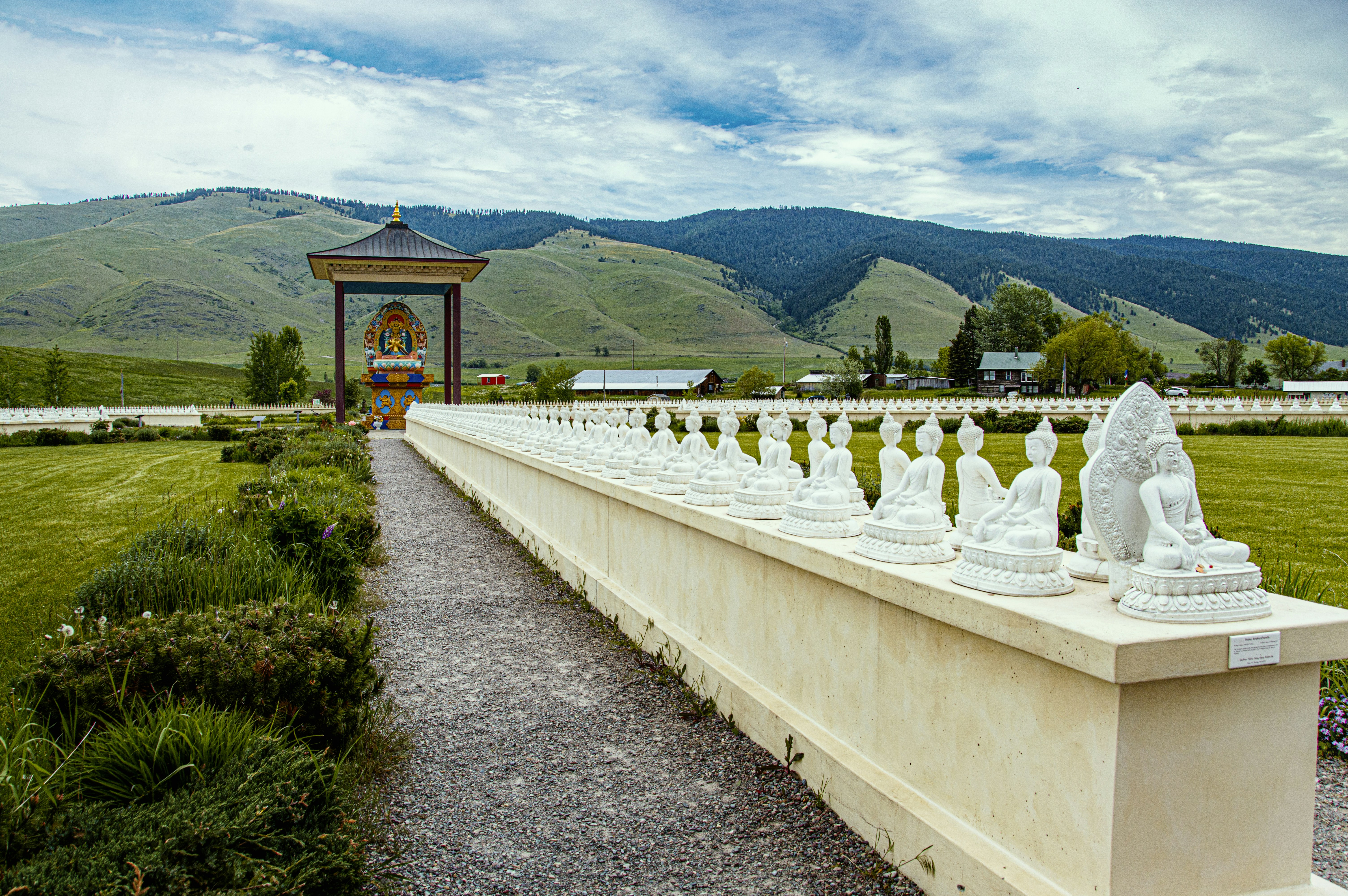 a stone wall with statues and a building in the background