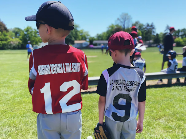 Young players in redbird uniforms sharing a high-five after a game on a sunny day.