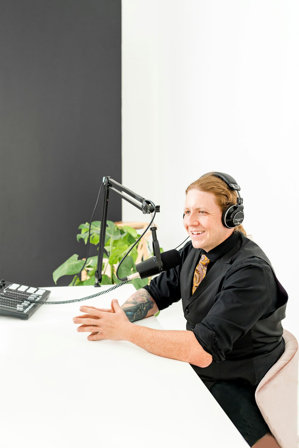 eine Person, die Kopfhörer trägt und an einem Schreibtisch mit Mikrofon sitzt