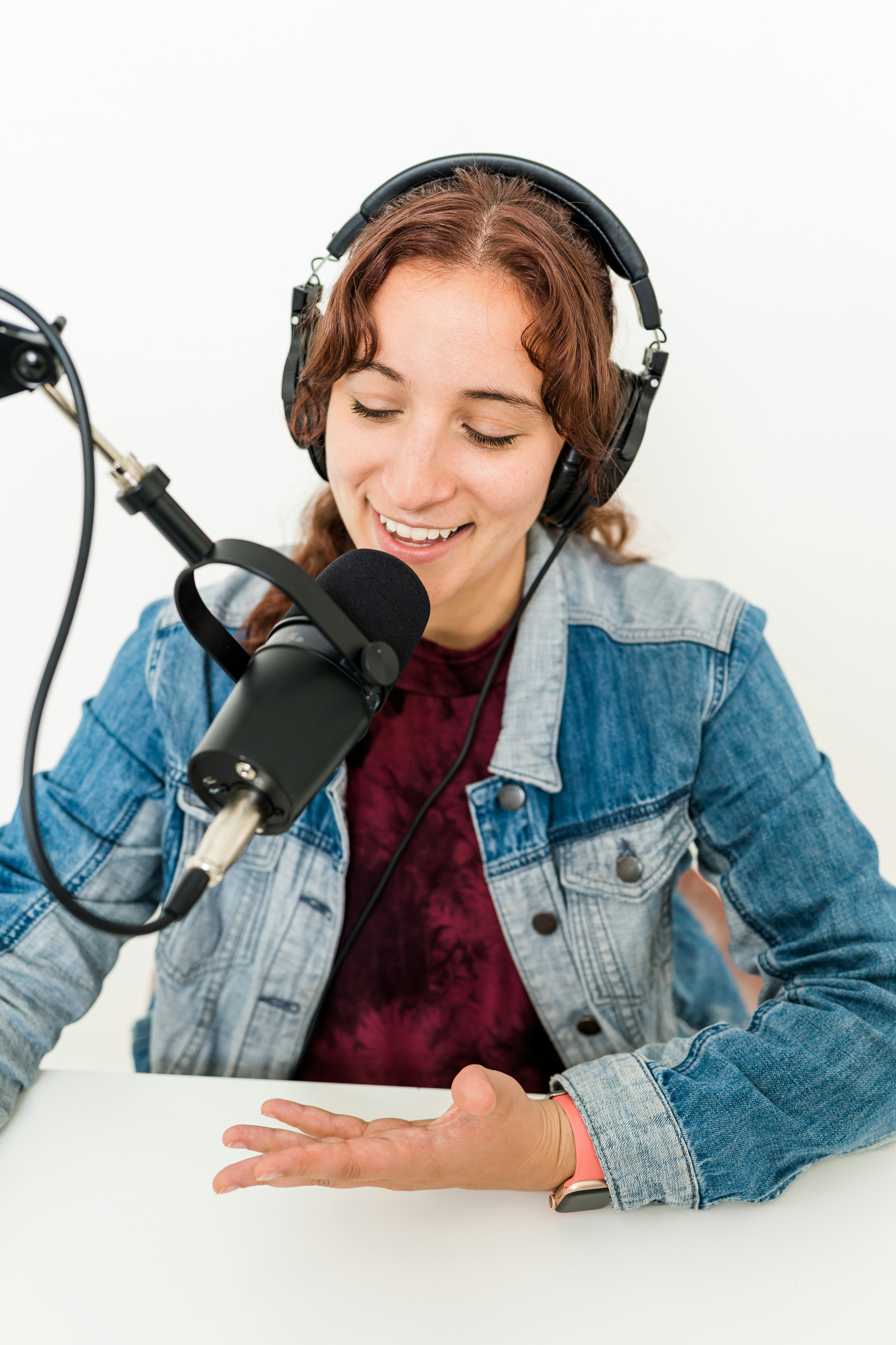 Woman smiling gesturing recording podcast with microphone