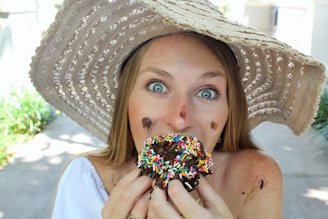 A happy customer enjoying a mini donut in a sunny park.