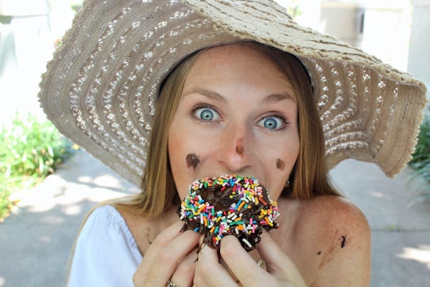 A happy customer enjoying a mini donut in a sunny park.