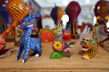 Brightly painted alebrijes displayed on a rustic wooden table.