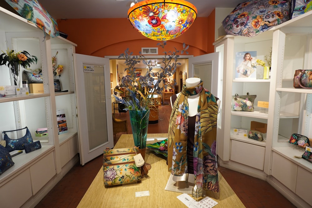 a room with a large display of clothing and a vase of flowers