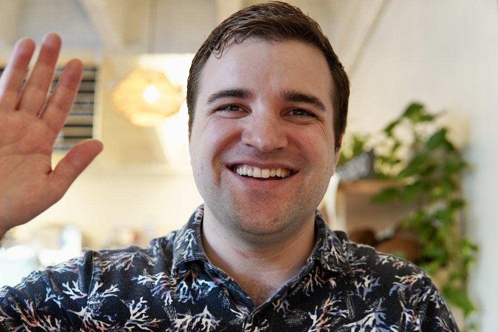 a man smiling and holding up a peace sign