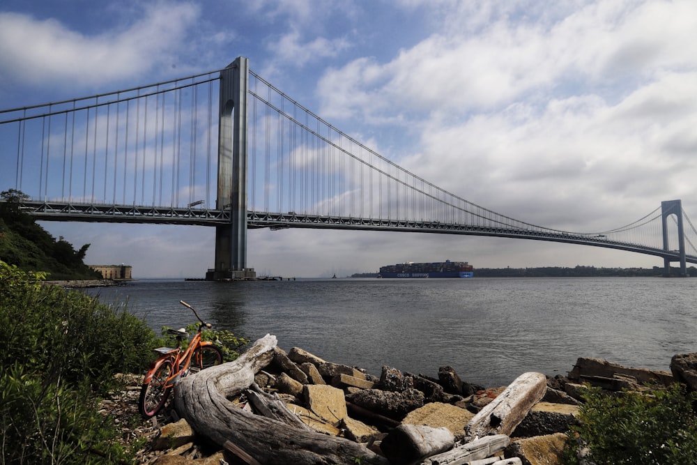 a bicycle parked on a rock by a bridge