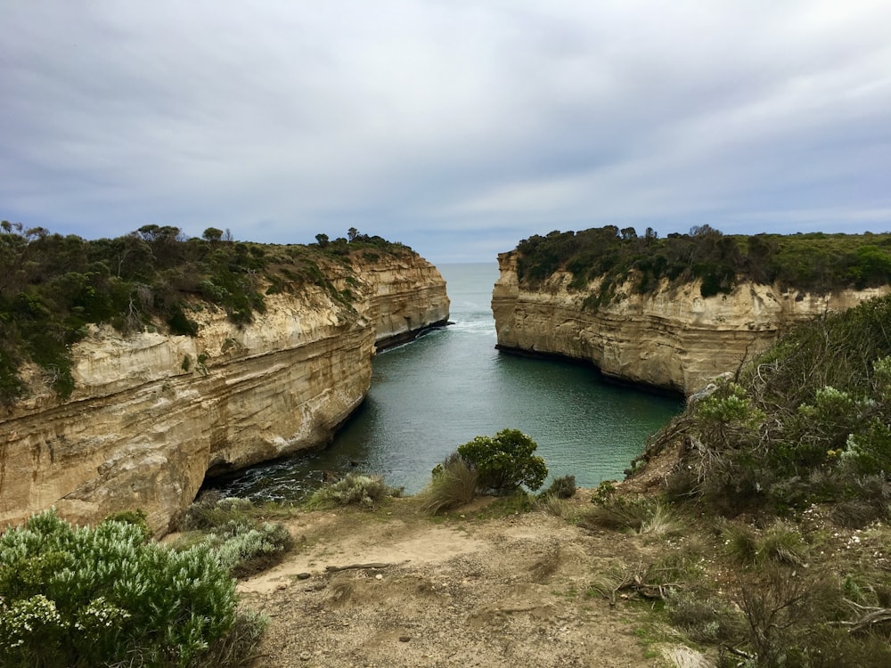 a body of water with cliffs on the side with Loch Ard Gorge in the background