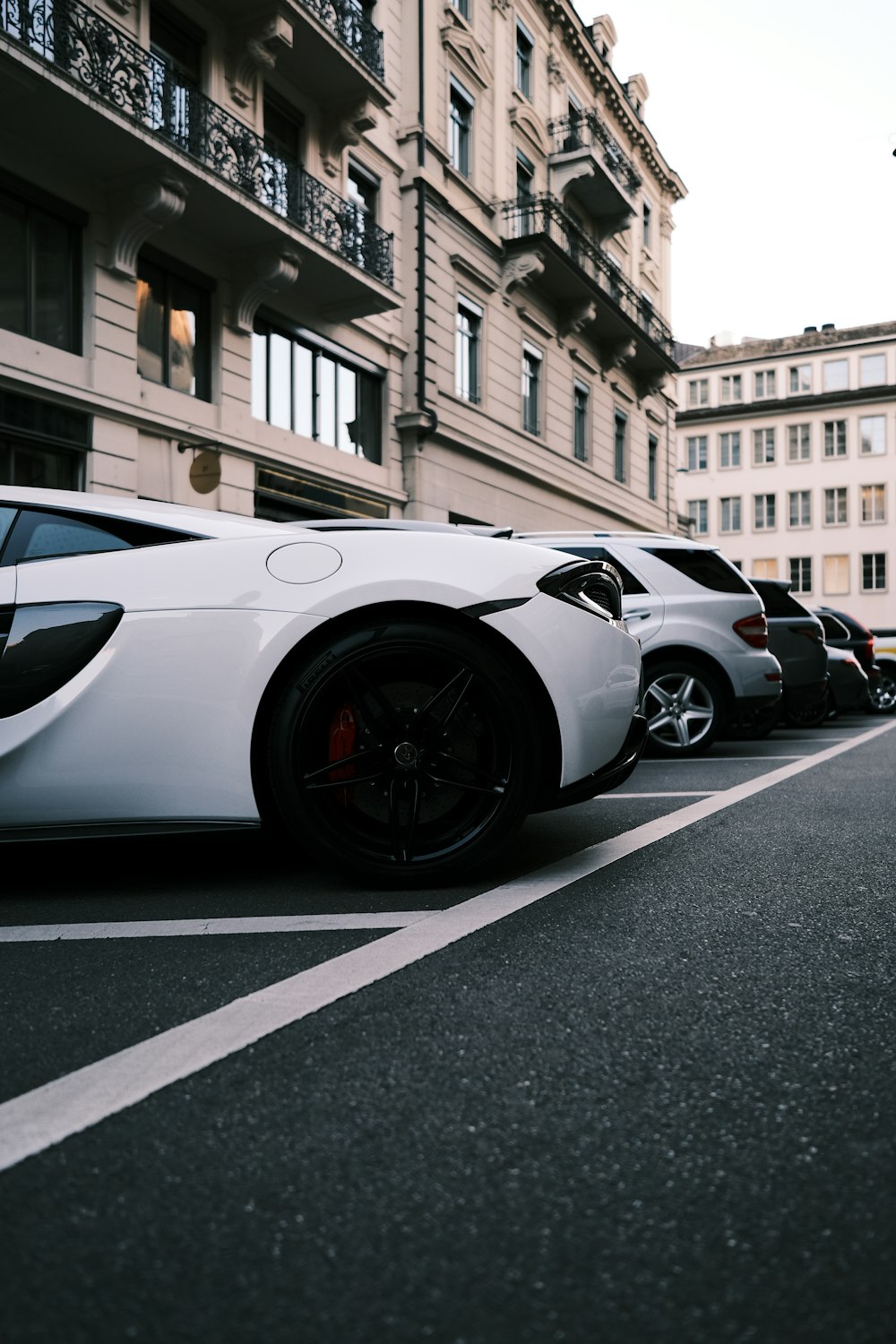 a white sports car parked in a parking lot next to a building