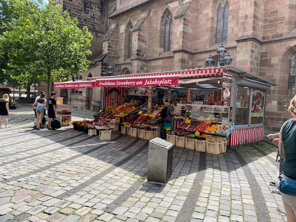 a fruit stand with people walking around