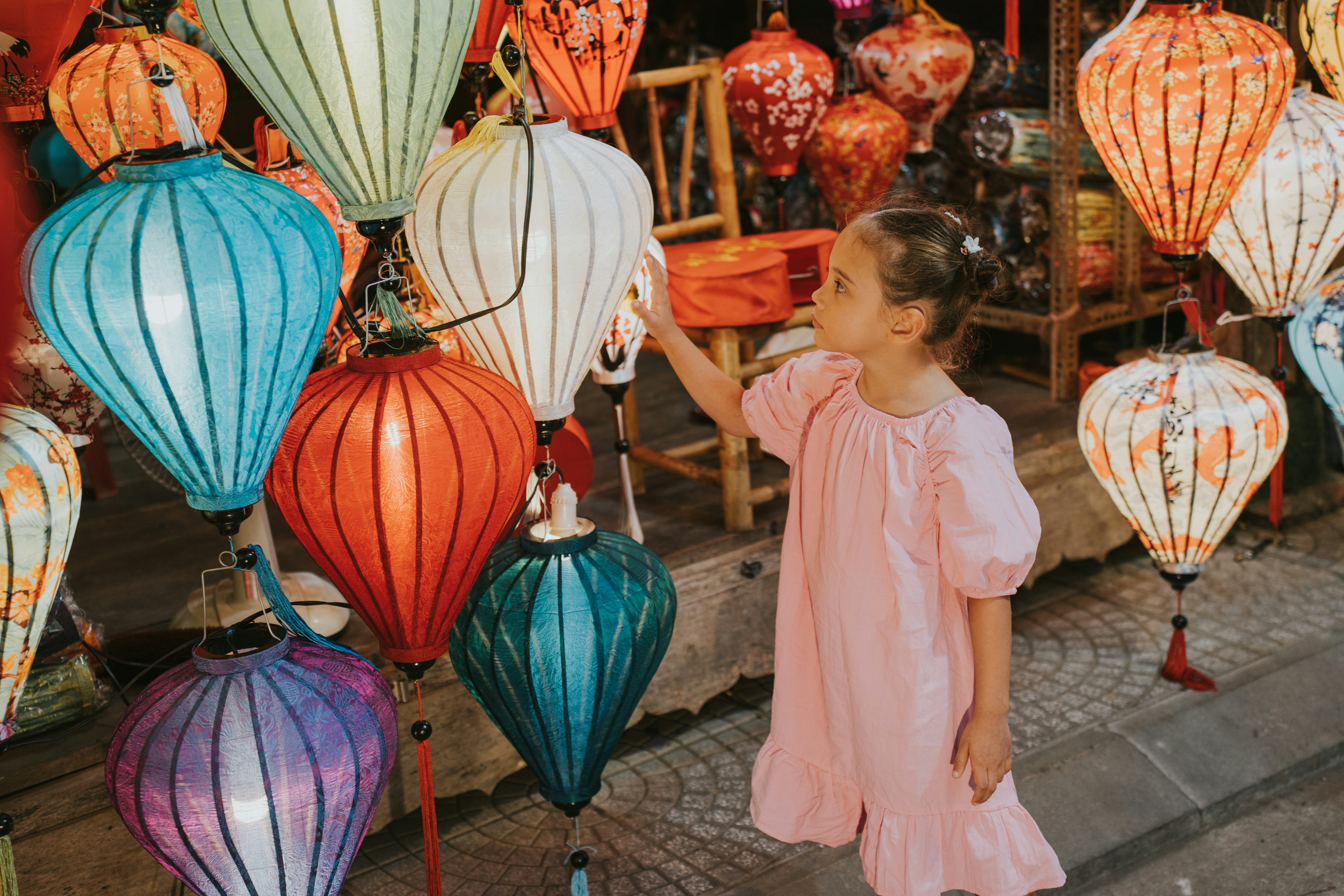 A little girl standing next to a display of colorful lanterns photo ...