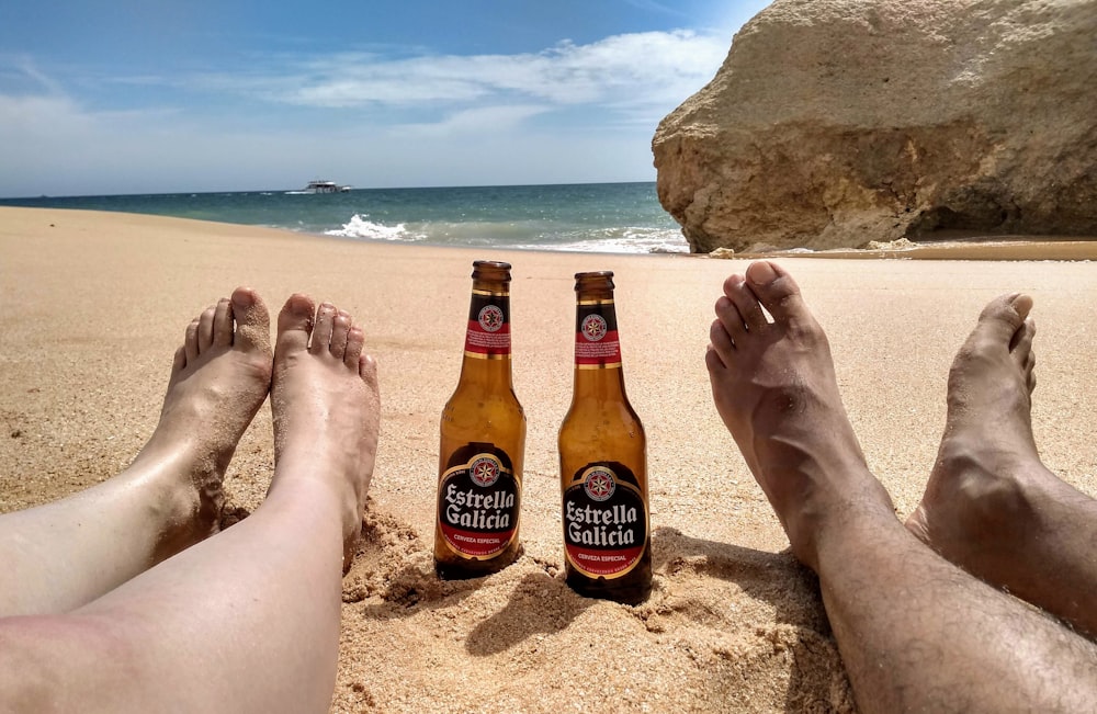 a group of people sitting on a beach with beer bottles