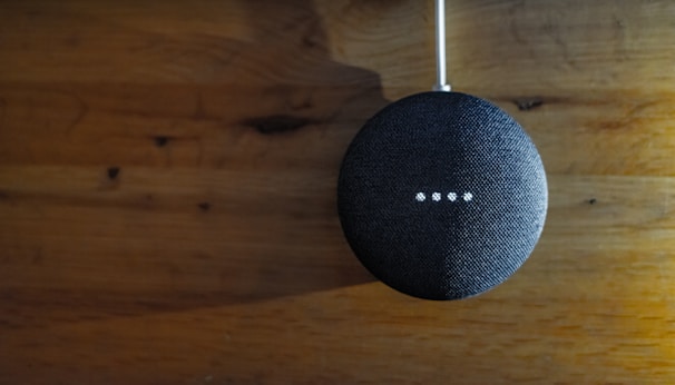A voice-controlled smart speaker sitting on a wooden kitchen counter.