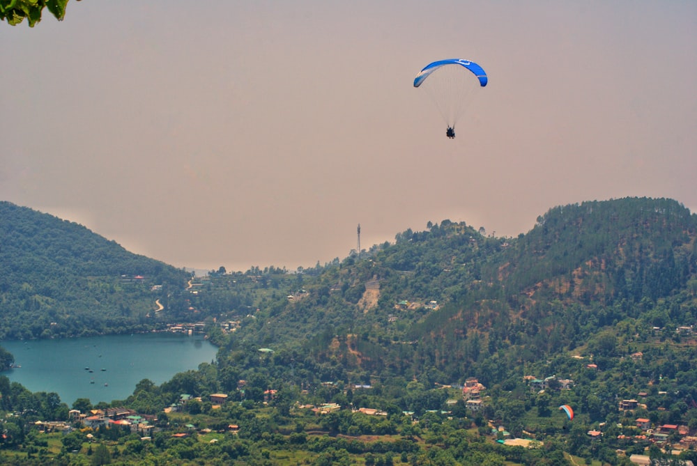 um casal de pessoas saltando de paraquedas sobre uma cidade à beira de um lago