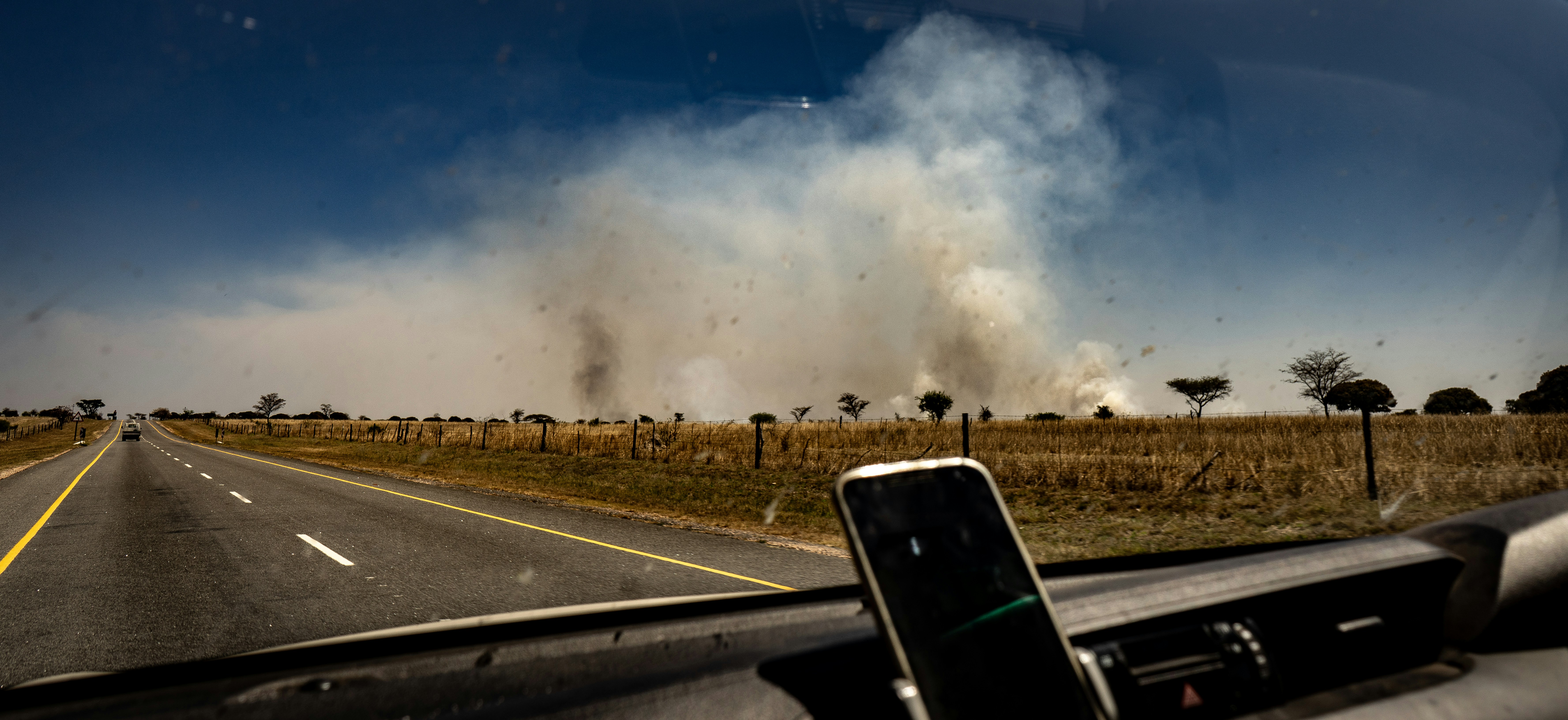 a road with a large cloud of smoke in the distance