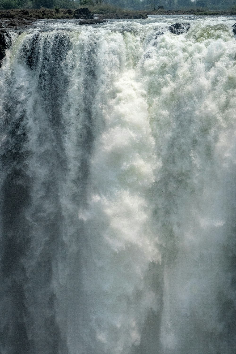 a large waterfall with trees in the background