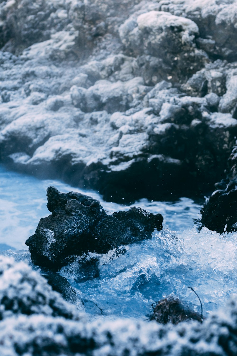 a pile of snow next to a waterfall