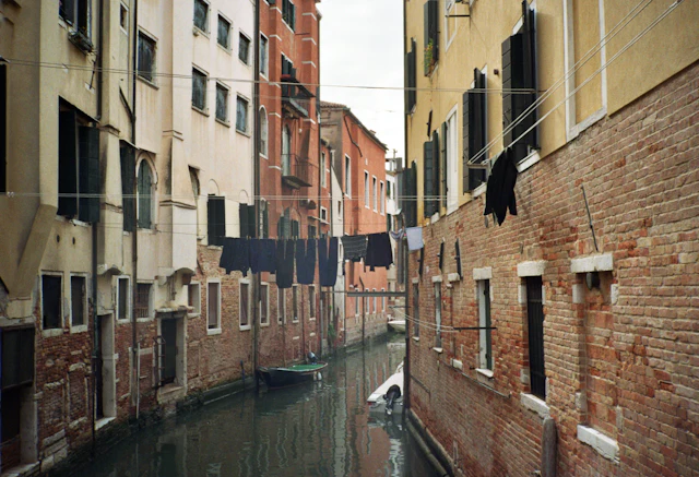 A narrow canal in the Jewish Ghetto flanked by unusually tall tenement buildings with laundry lines strung across.