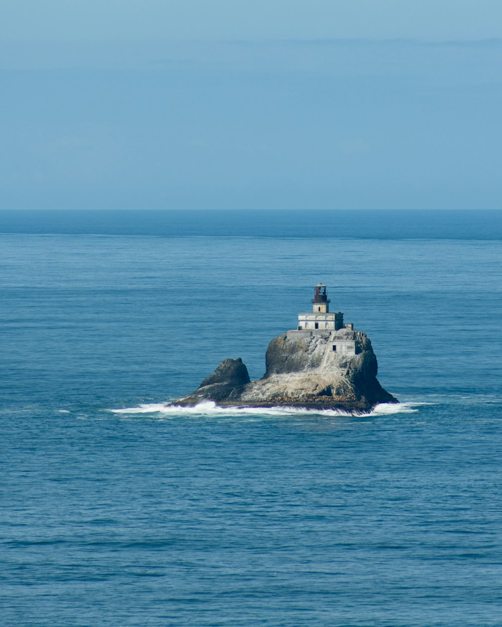 a lighthouse on a rock in the middle of the ocean