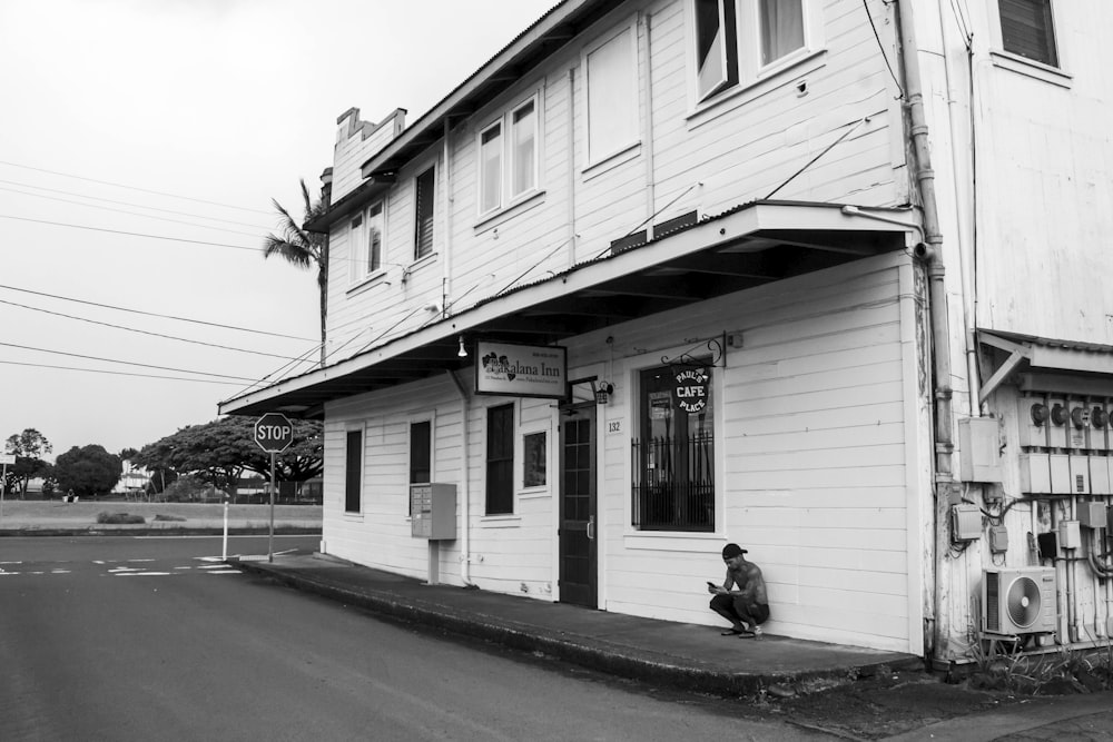 a person sitting on the side of a road next to a building