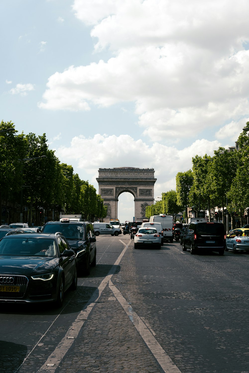 a road with cars on it and a large arch in the background