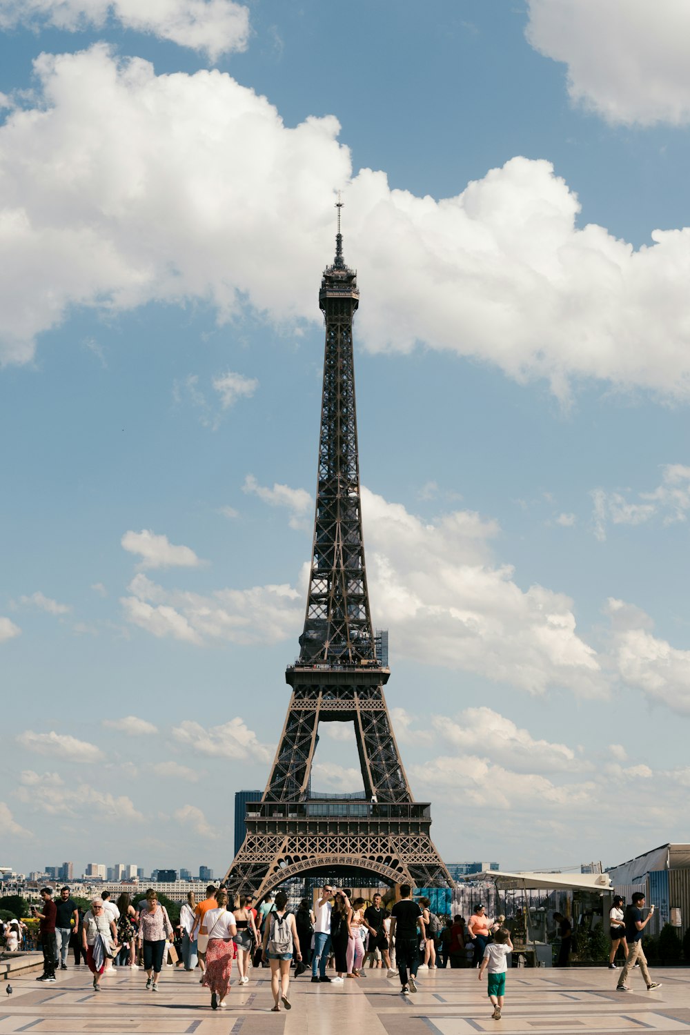 una grande torre di metallo con la Torre Eiffel sullo sfondo