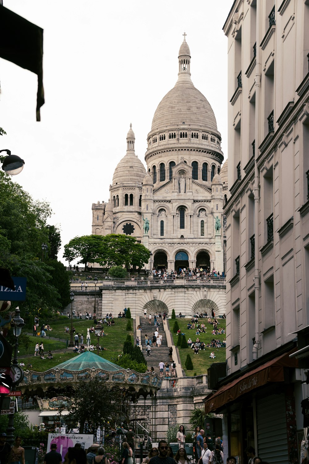 a large building with a dome and many people walking around with Sacré-Cœur, Paris in the background