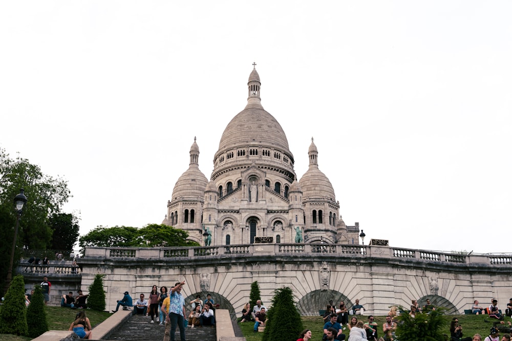 um grande edifício com uma cúpula e muitas pessoas em frente a ele com Sacré-Cœur, Paris ao fundo
