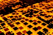 Abstract scene featuring a glowing geometric pattern of illuminated cubes and squares. The pattern is predominantly in shades of orange and black, creating a visually striking contrast. It resembles a digital or futuristic landscape, possibly representing a circuit board or a city at night.