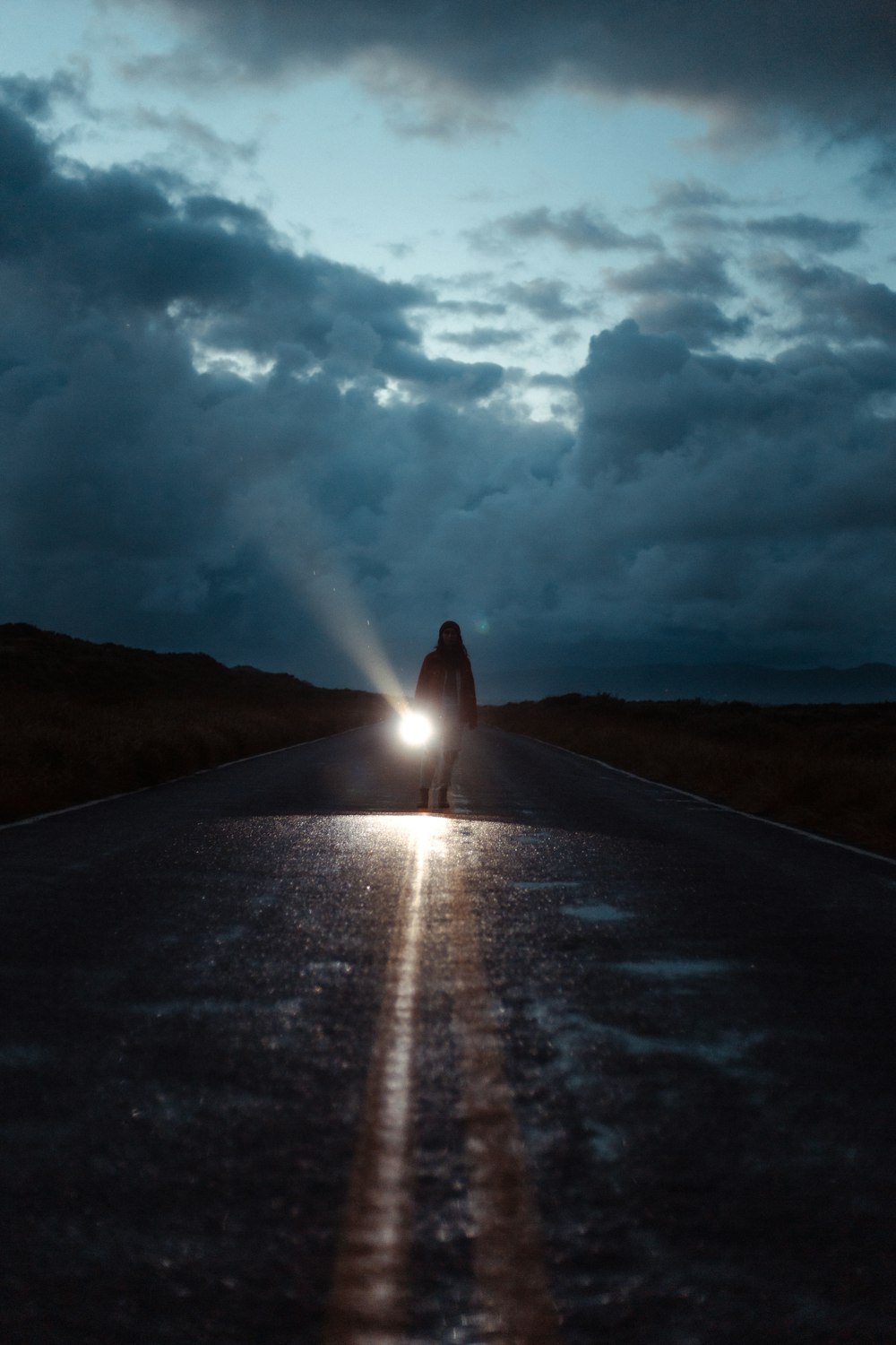 a person on a road with a bright light in the sky