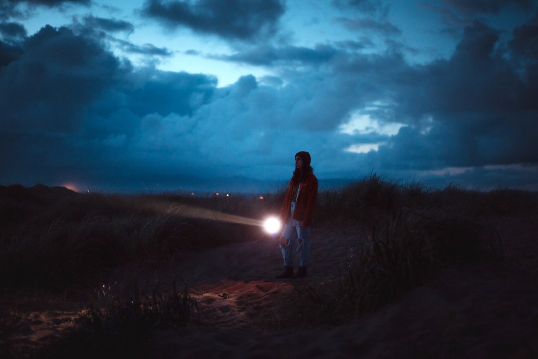 a person standing on a dirt path with the sun shining through clouds,