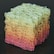 A complex, three-dimensional cube-shaped structure composed of interconnected, wireframe-like rectangular shapes. The structure features a gradient color scheme transitioning from shades of green at the top to yellow and pink at the bottom, set against a dark background.