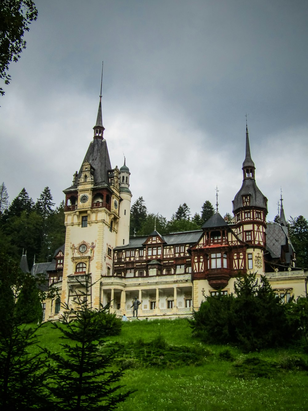 un gran edificio con torres con el castillo de Peleș al fondo