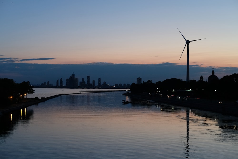 un plan d’eau avec un moulin à vent au loin